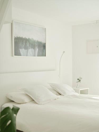 1 dormitorio blanco con 1 cama con una foto en la pared en Peak & Pause, en Bistrica pri Limbušu