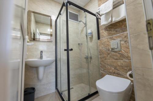 a bathroom with a shower and a toilet and a sink at Otel 57 in Sinop