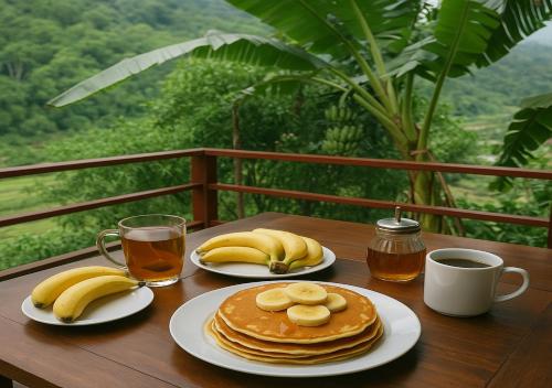 Dos platos de panqueques y plátanos en una mesa de madera. en Pu Luong Riverside Lodge, en Hương Bá Thước