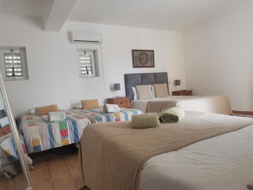 una stanza con tre letti in una stanza di Casa do Trovador a Serra