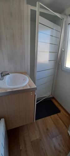 La salle de bains est pourvue d'un lavabo et d'une porte avec fenêtre. dans l'établissement Mobilhome 4 personnes 2 chambres Camping 3 étoiles Ivry la Bataille, à Ivry-la-Bataille