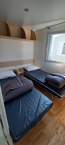 deux lits superposés dans une chambre avec fenêtre dans l'établissement Mobilhome 4 personnes 2 chambres Camping 3 étoiles Ivry la Bataille, à Ivry-la-Bataille