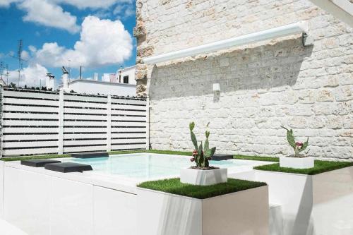 a swimming pool with two cactuses and a brick wall at Ulivi Bianchi Luxury Home in Puglia in Putignano
