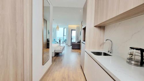 a kitchen with a sink and a living room at Elegant Apartment Alacarte Hạ Long in Ha Long
