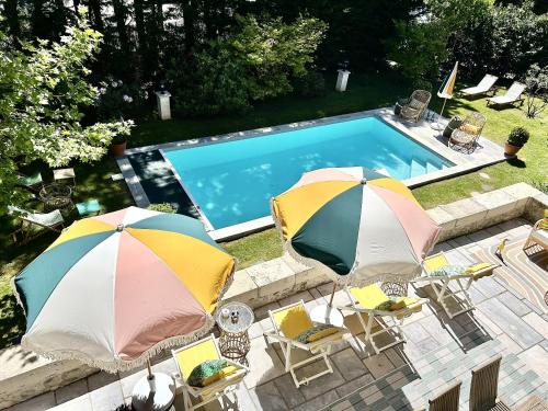 - deux parasols et des chaises à côté de la piscine dans l'établissement Maison Cuevas, à Biarritz