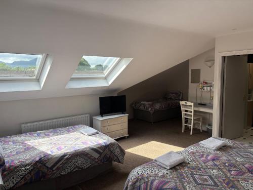 a attic room with two beds and a television at Harmony Inn - Glena House in Killarney