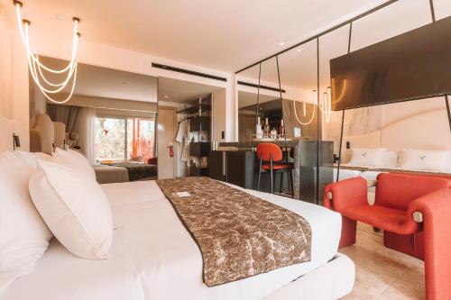 a bedroom with a white bed and a red chair at The Unexpected Ibiza Hotel - Ushuaïa Club entrance included in Playa d'en Bossa