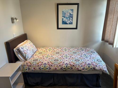 a bedroom with a bed with a floral comforter at Harmony Inn - Glena House in Killarney