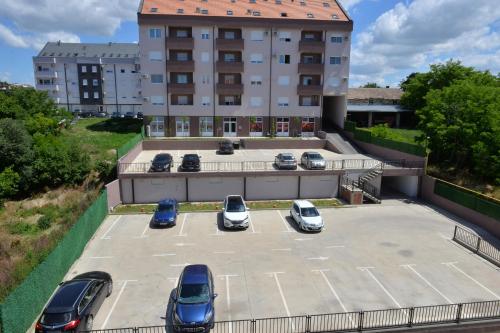 a parking lot with cars parked in front of a building at HM Apartments in Inđija