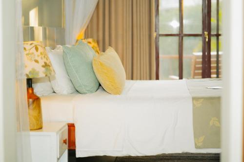 a white bed with colorful pillows on top of it at Arusha Planet Lodge in Arusha