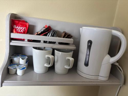 a shelf with coffee mugs and a book at Harmony Inn - Glena House in Killarney