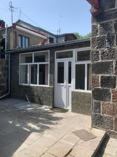 een huis met een witte deur en witte ramen bij Tuff House in Gjoemri
