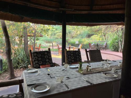 a table with a blue tablecloth and chairs with a view of a patio at Phokoje Bush Lodge in Selebi-Pikwe