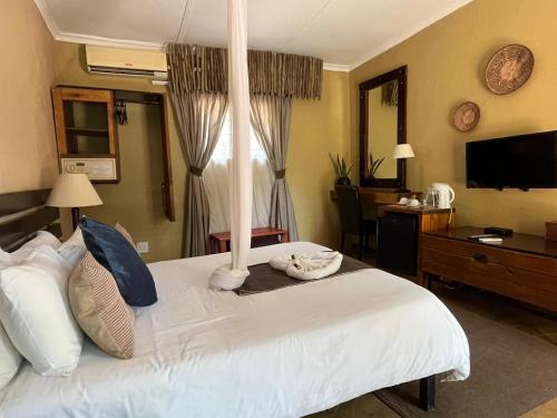 a bedroom with a large white bed and a television at Phokoje Bush Lodge in Selebi-Pikwe