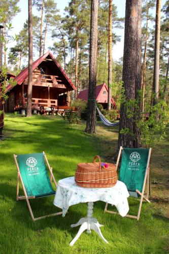 a picnic table with a basket and two chairs in a yard at Perła in Stegna