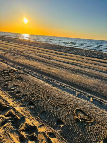 an inscription in the sand on a beach at sunset at Perła in Stegna