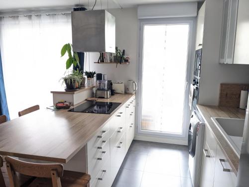 une cuisine avec des armoires blanches et un comptoir en bois dans l'établissement Appartement familial piscine - Proche gare et tram, à Bordeaux