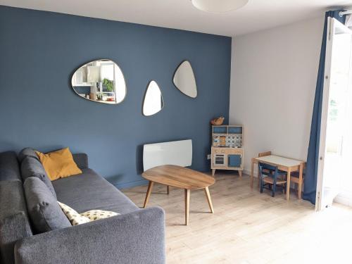 un salon bleu avec un canapé et une table dans l'établissement Appartement familial piscine - Proche gare et tram, à Bordeaux