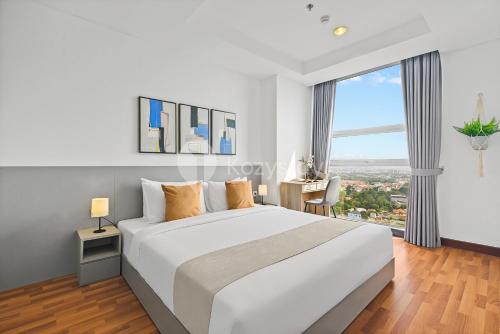 a bedroom with a white bed and a large window at Halia by Kozystay - Pondok Indah in Jakarta