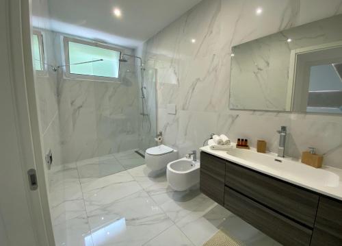 a white bathroom with a toilet and a sink at Villa Serafina in Otranto