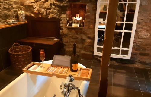 a bathroom with a bath tub with a bottle of wine at The Bothy, wood fired hot tub, luxury spa bathroom in St Asaph