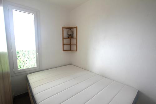 une chambre blanche avec un lit et une fenêtre dans l'établissement Studio Cabine en frond de mer, à Canet