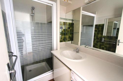 une salle de bain blanche avec un lavabo et un miroir dans l'établissement Studio Cabine en frond de mer, à Canet