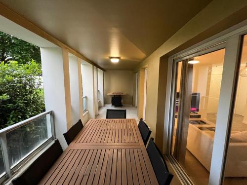 Cette chambre dispose d'une table en bois et d'un balcon. dans l'établissement T2 moderne avec terrasse, proche de Lyon, à Vaulx-en-Velin