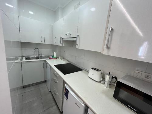 a white kitchen with white cabinets and a sink at Matiko habitaciones in Bilbao