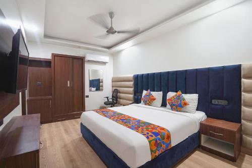 a bedroom with a large bed with a blue headboard at FabHotel Golden Eye Inn in New Delhi