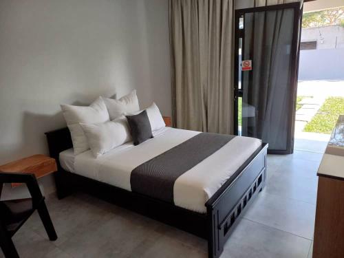 a bedroom with a bed and a table and a window at Pine Leaf Apartments in Lusaka