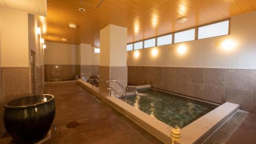 a bathroom with a bath tub and a large bath tub at HOTEL SANSUI NAHA Ryukyu Onsen Naminoue-No-Yu in Naha
