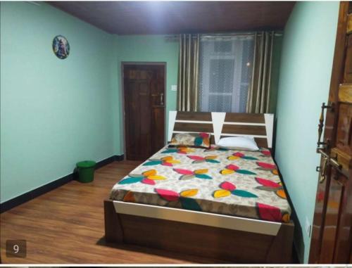 a bedroom with a bed with a colorful comforter at Arms Homestay & Girls Hostel in Kurseong