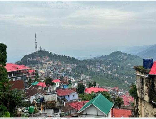 a view of a city with houses and a mountain at Arms Homestay & Girls Hostel in Kurseong