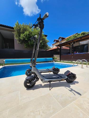 a scooter parked next to a swimming pool at Villa Jana in Kolan