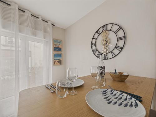 une table avec des verres et une horloge sur le mur dans l'établissement Appartement pour 2 en plein centre ville, à Concarneau