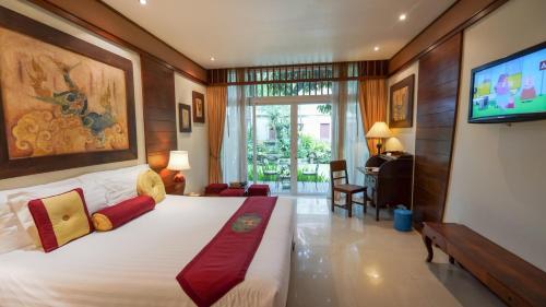 Un dormitorio con una cama grande y un televisor. en Kodchasri Thani Hotel Chiangmai, en Chiang Mai