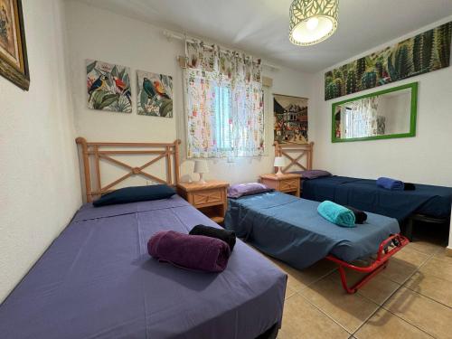 two beds in a room with purple sheets and pillows at VILLA SISSI Atlantic View in Costa Del Silencio