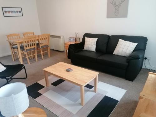 a living room with a black couch and a table at House in Alness in Alness