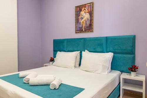 a bed with a blue headboard and two towels at Roan Apartments in Sarandë