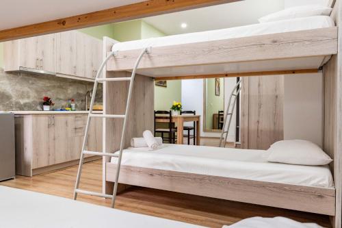 a bedroom with two bunk beds and a kitchen at Roan Apartments in Sarandë