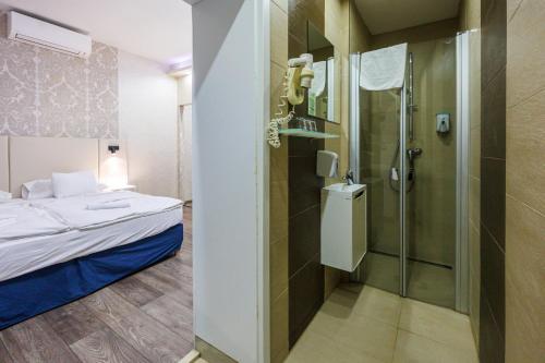 a bathroom with a shower and a bed in a room at Bástya Konferencia és Wellness Hotel in Miskolctapolca