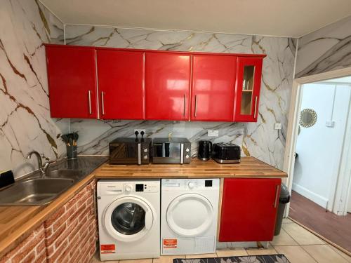 a kitchen with red cabinets and a washing machine at BB-Spacious 1 Double room in Wembley in London