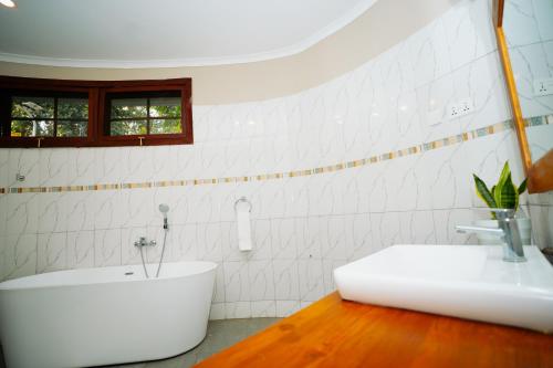 a white bathroom with a tub and a sink at Arusha Planet Lodge in Arusha