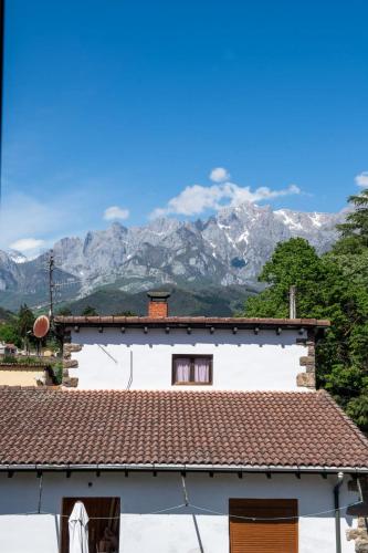 a white house with mountains in the background at La casa de Chachi in Potes