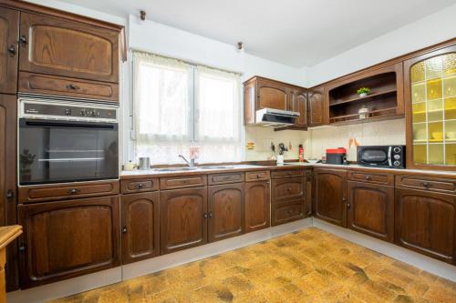 a large kitchen with wooden cabinets and a window at La casa de Chachi in Potes