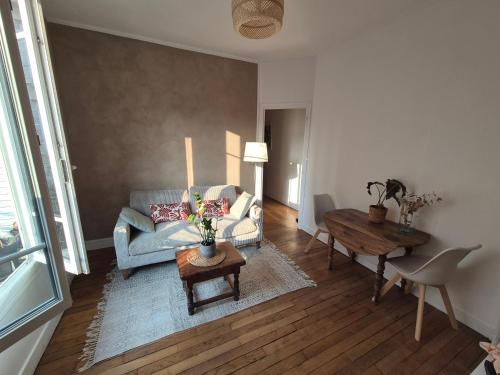 a living room with a couch and a table at Charmant T2 avec cachet - Au cœur de Poissy & à 20 min de Paris ! in Poissy