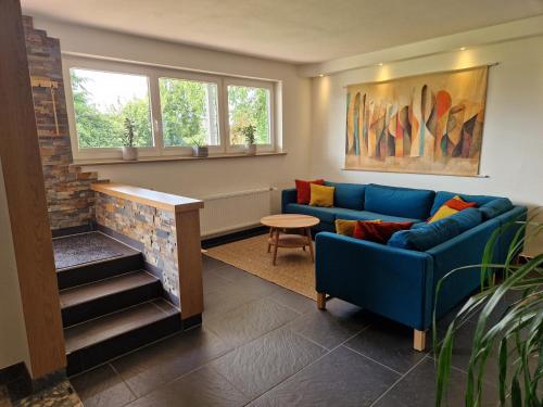 a living room with a blue couch and a fireplace at Löhgarten in Kleinmaischeid