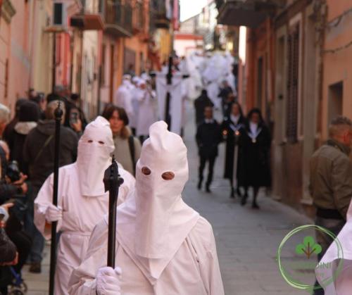 two people dressed in white walking down a street at Casa vacanze i Giardini Iglesias in Iglesias