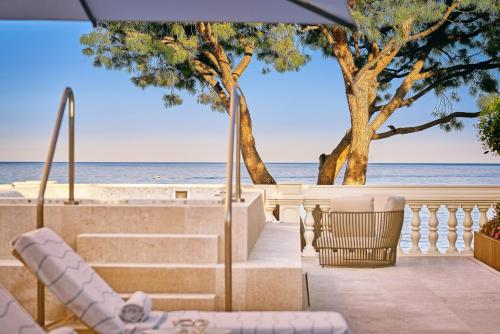 a view of the beach from a resort with chairs and an umbrella at La Réserve de Beaulieu in Beaulieu-sur-Mer